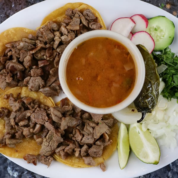 Three Mexico Lindo Restaurant carne asada tacos with a side of broth, grilled pepper, and garnishes.