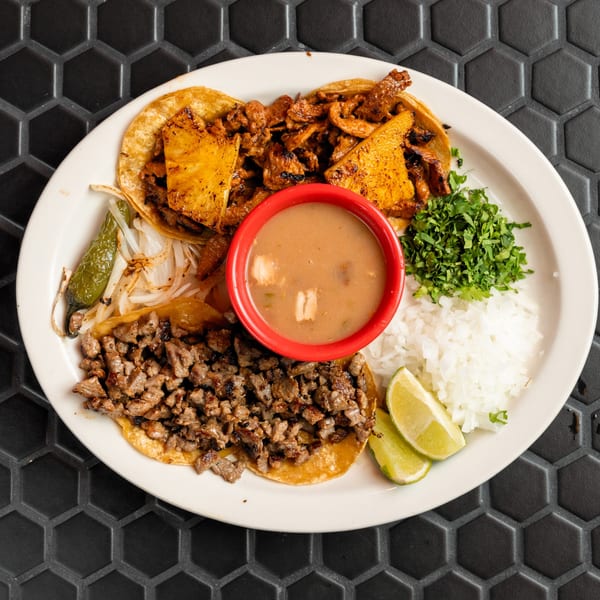 Mexico Lindo's plate of al pastor and carne asada tacos with rice, cilantro, onions, and lime.