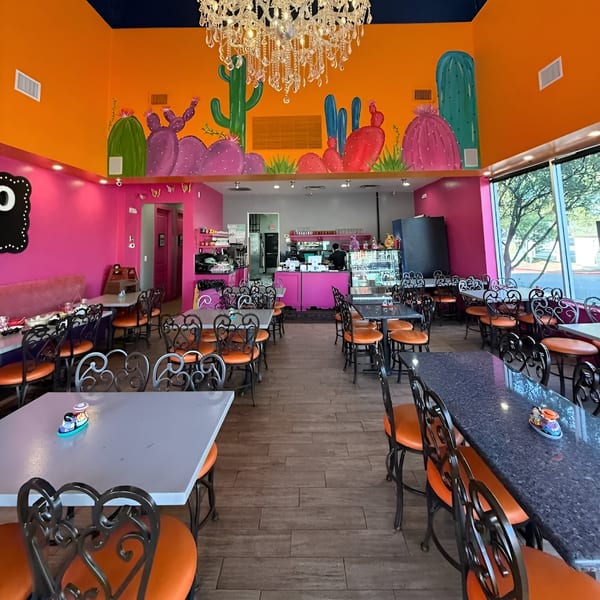Vibrant Mexico Lindo Restaurant interior with orange and pink walls, cactus murals, and empty tables.