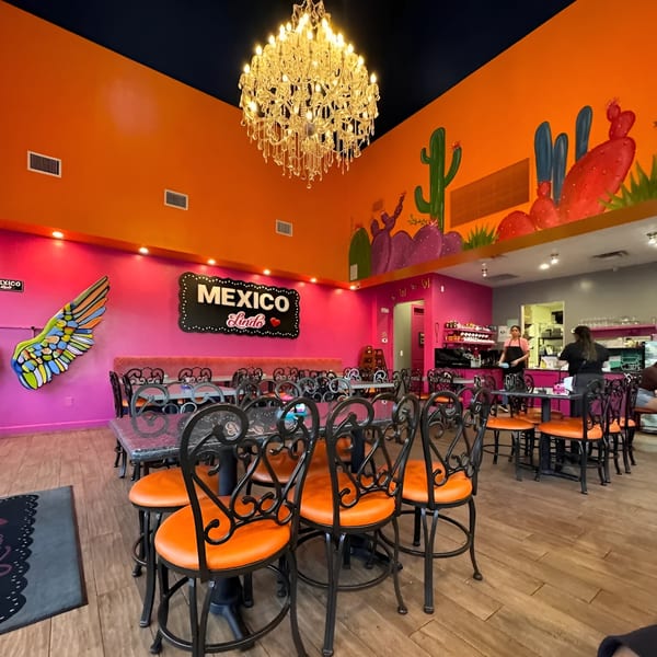 Vibrant Mexico Lindo Restaurant interior with orange and pink walls, cactus murals, and a large chandelier.