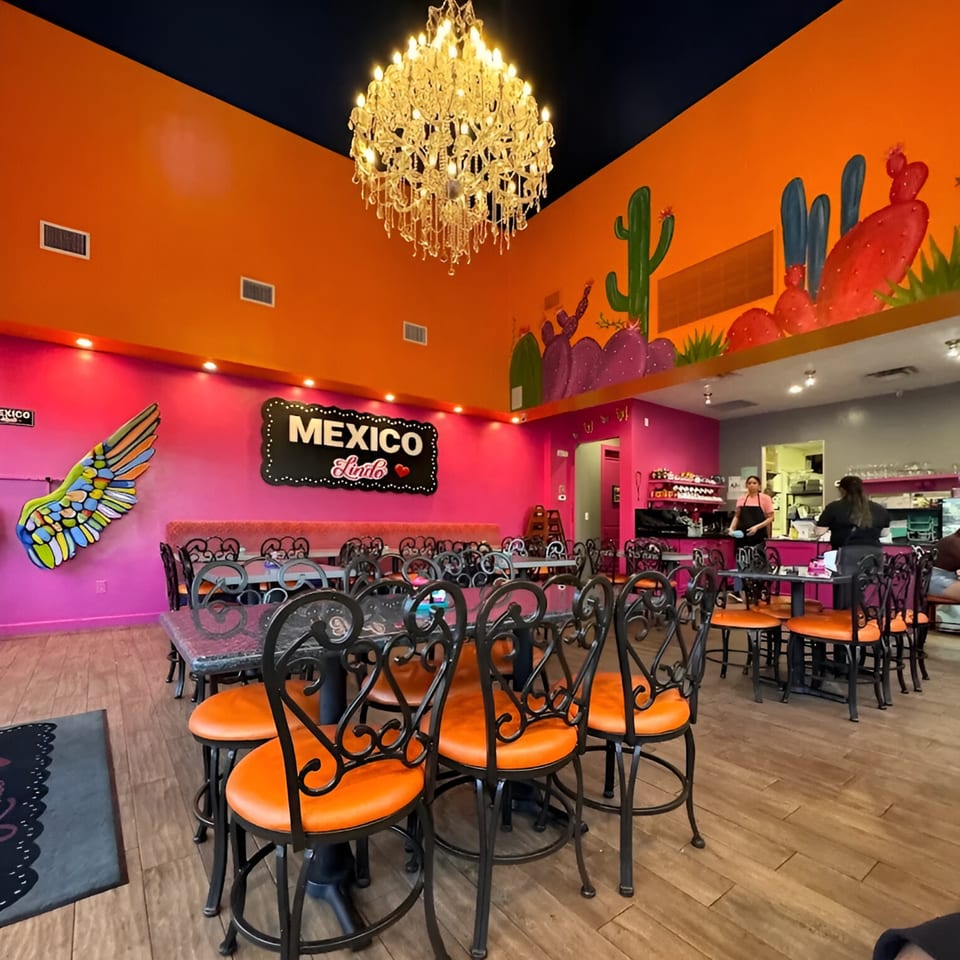 Vibrant Mexico Lindo Restaurant interior with orange and pink walls, cactus murals, and a large chandelier.